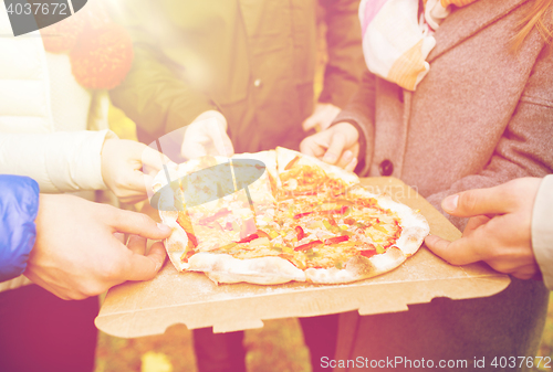 Image of close up of friends hands eating pizza outdoors