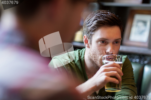 Image of happy man with friend drinking beer at bar or pub