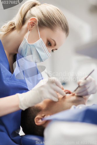 Image of female dentist checking up male patient teeth