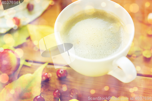 Image of close up of coffee cup on table with autumn leaves