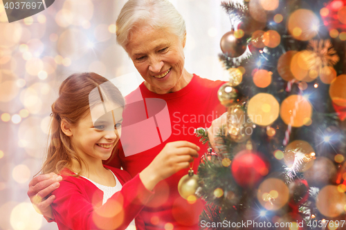 Image of smiling family decorating christmas tree at home