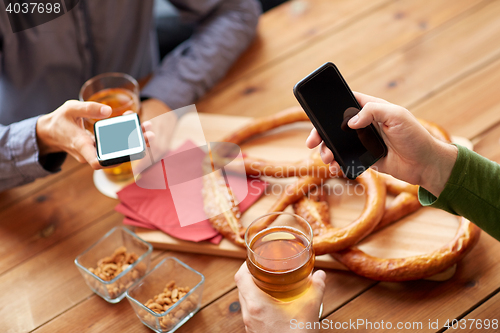 Image of close up of hands with smartphones and beer at bar