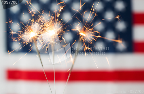 Image of close up of sparklers burning over american flag