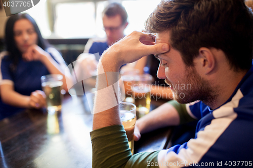 Image of soccer fans watching football match at bar or pub