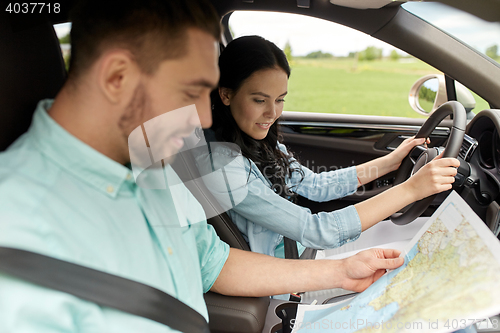 Image of happy man and woman with road map driving in car