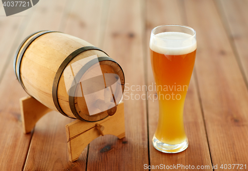 Image of close up of beer glass and wooden barrel on table