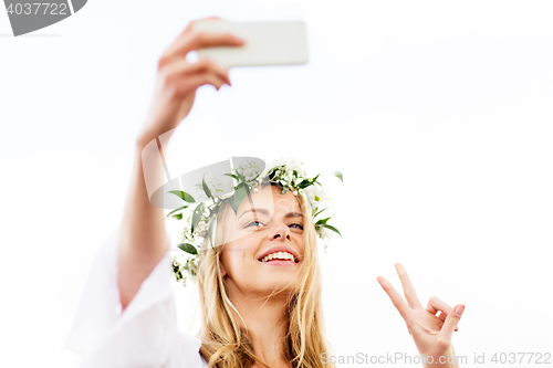 Image of woman taking smartphone selfie and showing peace