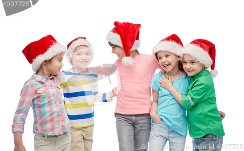 Image of happy little children in santa hats hugging