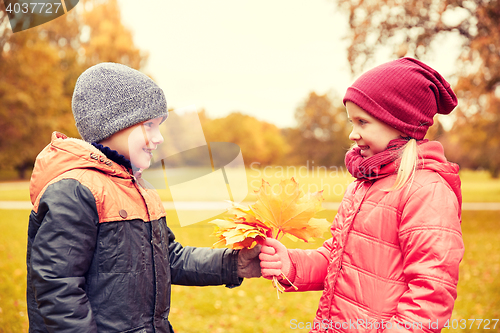 Image of little boy giving autumn maple leaves to girl