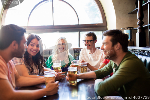 Image of happy friends drinking beer at bar or pub