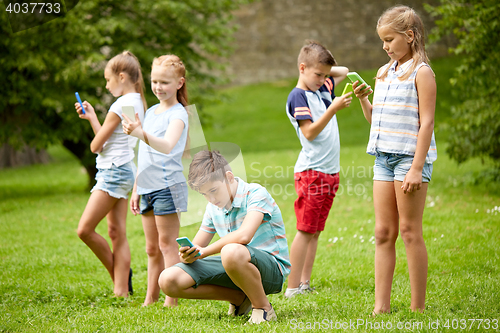 Image of kids with smartphones playing game in summer park