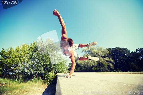 Image of sporty young man jumping in summer park