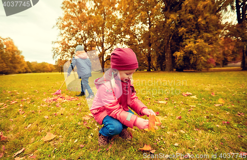 Image of children collecting leaves in autumn park