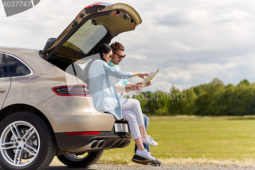 Image of happy man and woman with road map at hatchback car