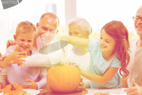 Image of happy family sitting with pumpkins at home