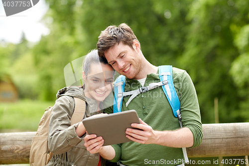 Image of happy couple with backpacks and tablet pc outdoors