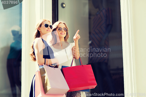 Image of happy women with shopping bags outdoors