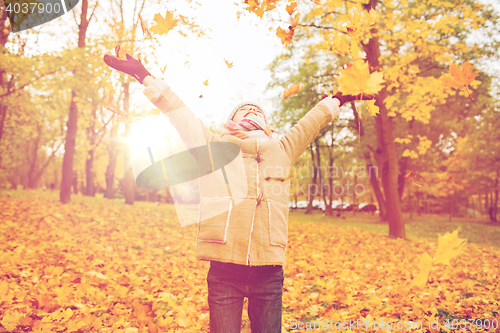 Image of smiling little girl with autumn leaves in park