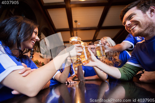 Image of football fans clinking beer glasses at bar or pub