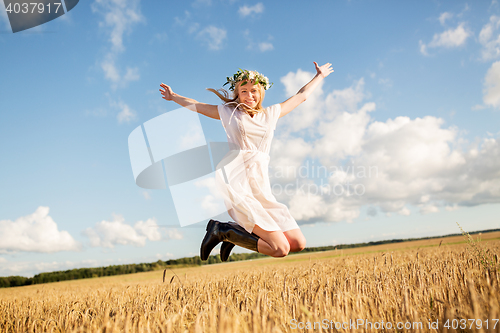 Image of happy woman in wreath jumping on cereal field