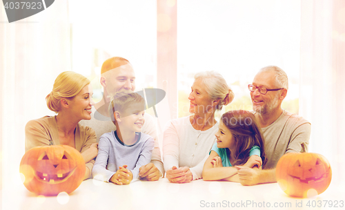 Image of happy family sitting with pumpkins at home