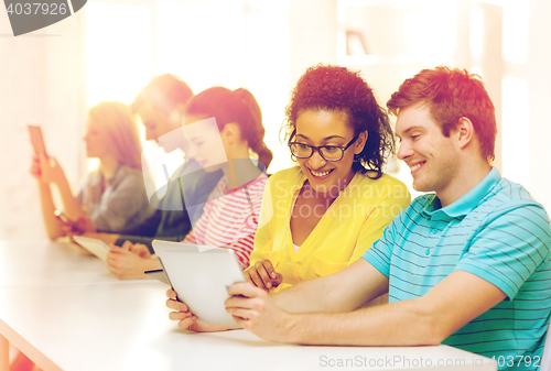 Image of smiling students looking at tablet pc at school