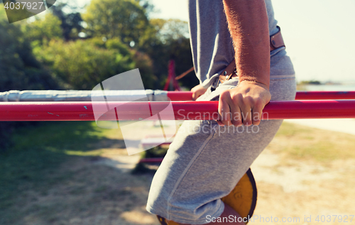 Image of young man exercising on parallel bars outdoors