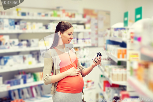 Image of happy pregnant woman with medication at pharmacy