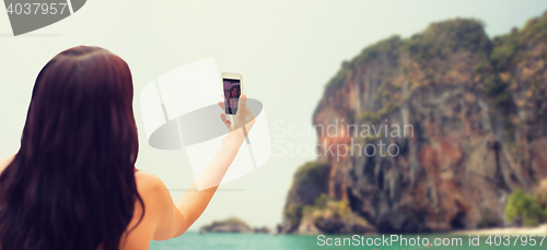 Image of young woman taking selfie with smartphone