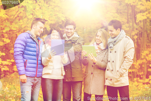 Image of group of smiling friends with tablets in park