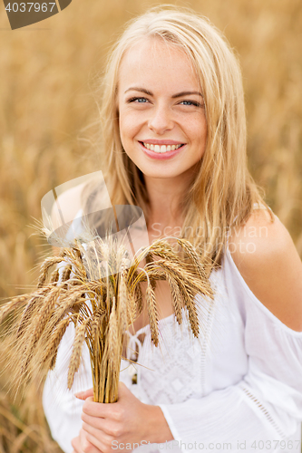 Image of happy young woman with spikelets on cereal field