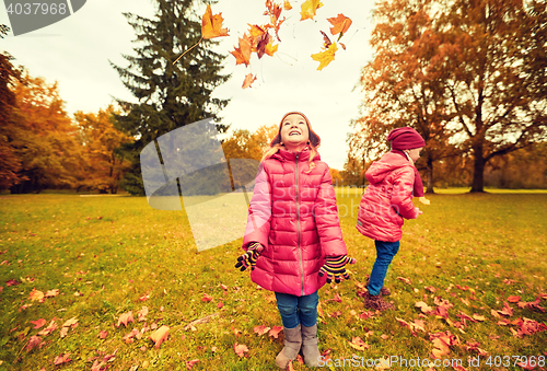 Image of happy children playing with autumn leaves in park