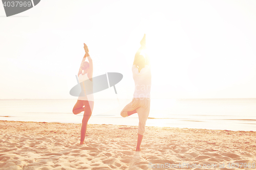 Image of couple making yoga exercises outdoors from back