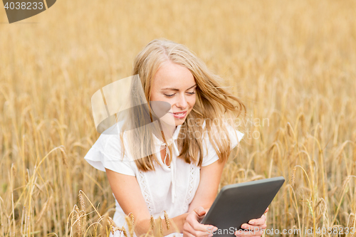 Image of happy young woman with tablet pc on cereal field