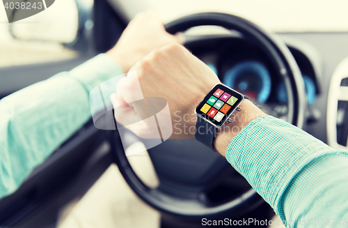 Image of close up of man with app on smartwatch driving car