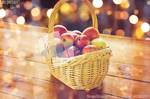 Image of close up of basket with apples on wooden table