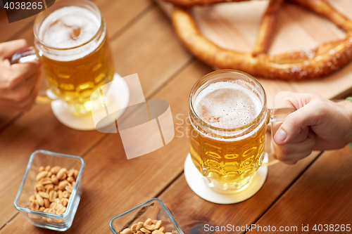 Image of close up of hands with beer mugs at bar or pub