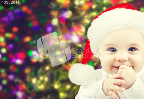 Image of happy baby in santa hat over christmas lights