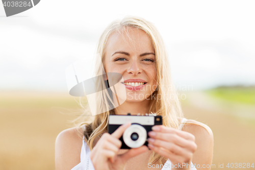 Image of happy young woman with film camera outdoors