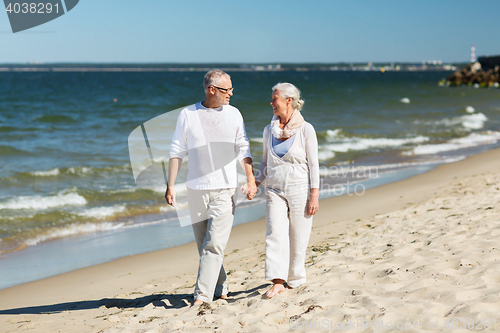 Image of happy senior couple holding hands on summer beach