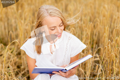 Image of smiling young woman reading book on cereal field