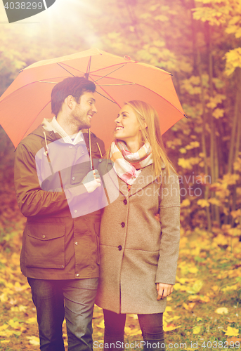 Image of smiling couple with umbrella in autumn park