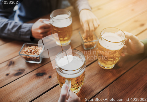 Image of close up of hands with beer mugs at bar or pub