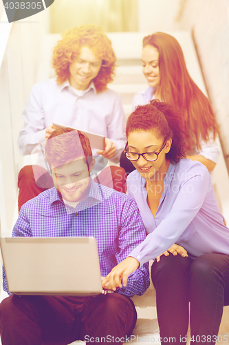 Image of team with laptop and tablet pc on staircase