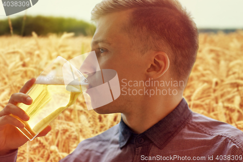 Image of close up of young man drinking beer from glass