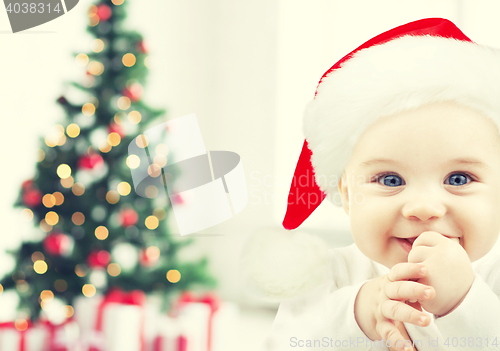 Image of happy baby in santa hat over christmas tree lights