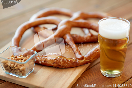 Image of close up of beer, pretzels and peanuts on table