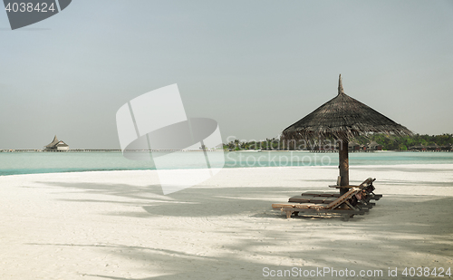 Image of palapa and sunbeds by sea on maldives beach