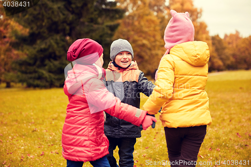 Image of children holding hands and playing in autumn park