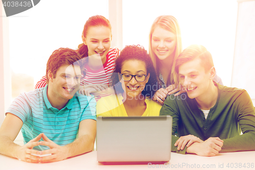 Image of smiling students looking at laptop at school